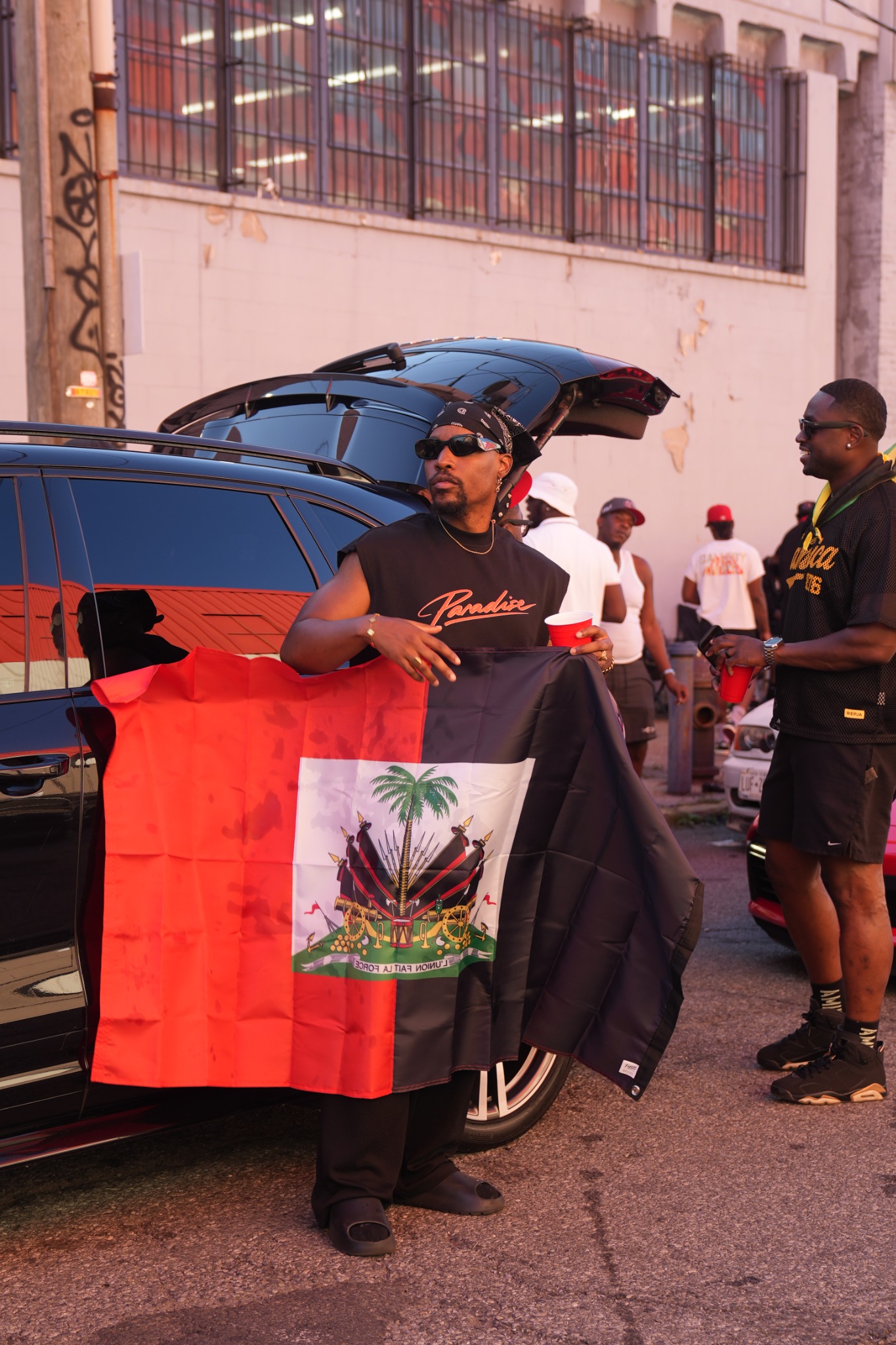 Guylaire holding the Haitian flag beside the parade gathering